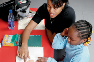 A tutor working with a young student representing CURAR research.