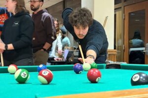 Student lining up a shot at the pool table